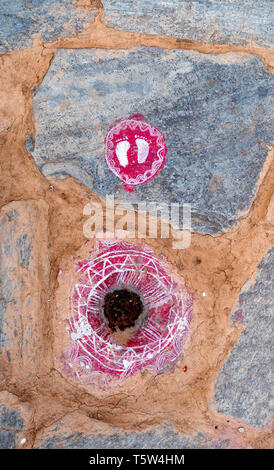 Orme della dea Lakshmi in bianco su un rosso roundel portando la ricchezza e la buona fortuna per la casa nel villaggio Supi in Uttarakhand Himalaya Foto Stock