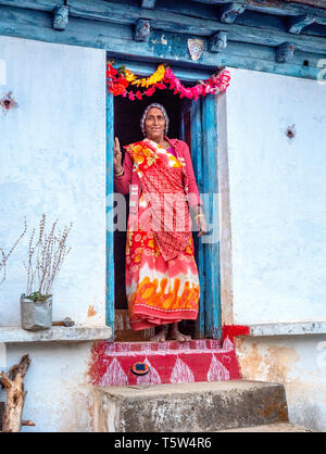 Donna sul decorate e blasonata soglia di casa in remoto villaggio di Satri nella regione di Binsar di Uttarakhand Himalaya Foto Stock