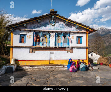 Un gruppo di abitanti seduti dalla coloratissima casa principale nel villaggio Supi in alta Valle Saryu dell'Uttarakhand Himalaya India del nord Foto Stock