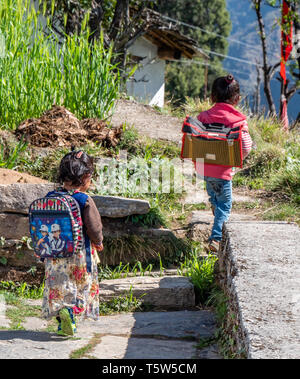 Due bambini piccoli sul loro modo di scuola nel villaggio di Supi nella valle Saryu di Uttarakhand in India del Nord Foto Stock