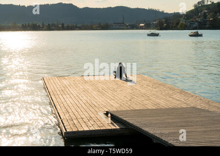 Silhouette di donna relax su un bacino galleggiante sul Lago Aegerisee in Svizzera al tramonto Foto Stock