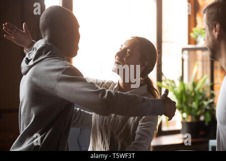 Biracial abbracciando la ragazza africana di guy amici radunati nella caffetteria Foto Stock