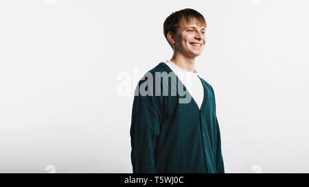 Allegro giovane con breve marrone capelli in piedi contro uno sfondo bianco. Allegro giovane uomo che guarda lontano. Foto Stock