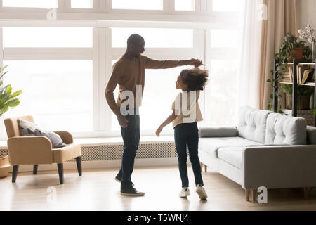 Nero padre tiene la figlia a mano la gente ballare in salotto Foto Stock