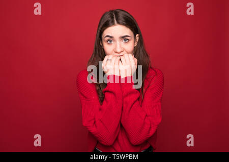 Ho paura. Spavento. Ritratto di donna spaventata. Business Woman Standing isolato sul rosso alla moda di sfondo per studio. Metà femmina-lunghezza verticale. Essere umano Foto Stock