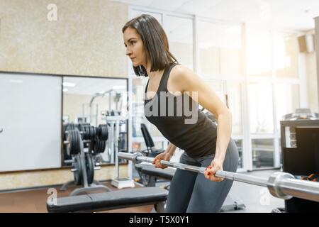 Giovane bella donna atletica brunette facendo esercizi di fitness in palestra. Fitness, sport, formazione, persone, uno stile di vita sano concetto Foto Stock