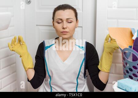 Stanco donna adulta pulizia wc bagno camera, donna chiudendo gli occhi, meditando di riposo. Foto Stock