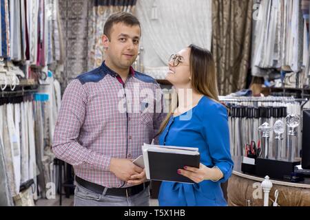 Paio di proprietari di negozio di tessuti per tende e interni, l uomo e la donna partner in posa, sfondo showroom tessuti interni. Foto Stock