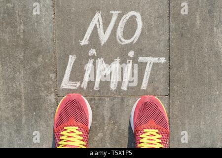 Nessun limite di testo grigio sul marciapiede con gambe di donna in sneakers, vista dall'alto. Foto Stock