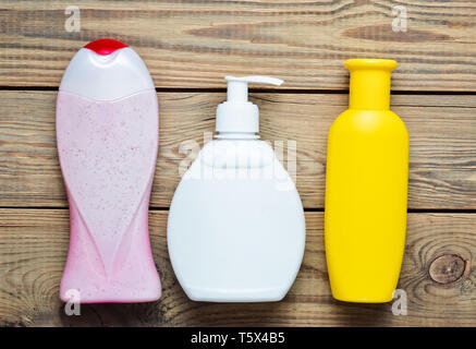 Bottiglie di prodotti per il bagno. Gel doccia, sapone, shampoo su un tavolo di legno. Vista dall'alto. Foto Stock
