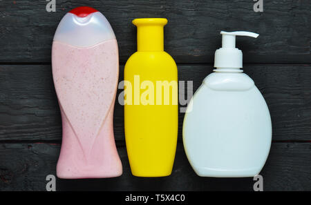 Bottiglie di prodotti per la doccia. Gel doccia, sapone, shampoo su tavoli in legno nero. Vista dall'alto. Foto Stock