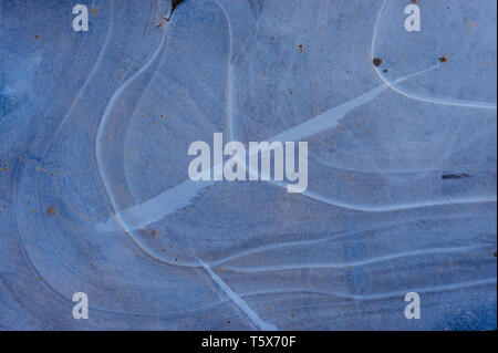 Dettaglio di una pozza congelati catturata su un gelido inverno mattina rivela forme astratte e modelli di strutture ghiacciate in bianco e blu Foto Stock