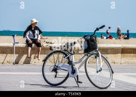 Valencia Malvarrosa Beach turista, donna anziana, bicicletta e gruppo di persone in background sulla spiaggia di sabbia, Spagna Europa vista mare Foto Stock