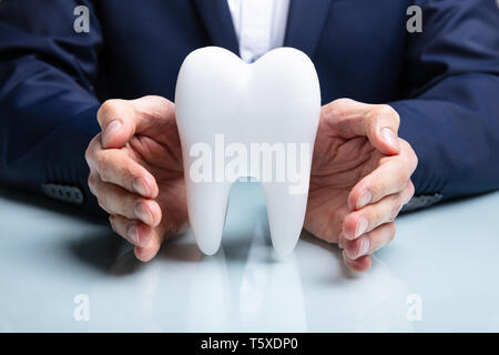 Mano d'uomo proteggere igienicamente sano Dente Bianco sul tavolo riflettente Foto Stock