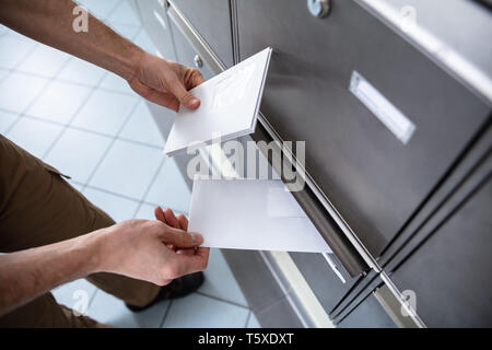 Close-up di mano d'uomo inserimento di lettere nella casella di posta Foto Stock