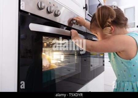 Bambina giocando con il sistema elettrico di un forno a microonde in cucina Foto Stock