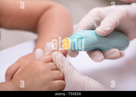 Taglio di madre il suo bambino dito unghie utilizzando Electronic Nail Trimmer Foto Stock