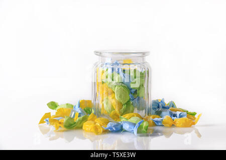 Aprire un vasetto di vetro con caramelle confezionate in ed intorno ad esso. Foto Stock