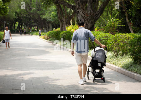 Uomo cinese persone spingendo il carrello e il bambino sulla strada nel giardino di Zhongshan parco pubblico di Shantou città o città Swatow maggio su 9, 2018 in Guangdong, Ch Foto Stock