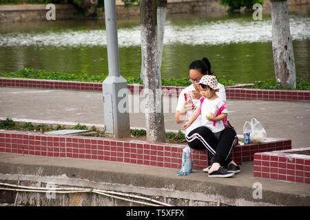 Il popolo cinese di alimentazione per alimentare di anatra e di fantasia o di carpe Koi pesci in laghetto di acqua nel giardino di Zhongshan Park in Shantou Swatow o città il 9 maggio 2018 Foto Stock