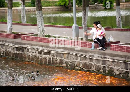 Il popolo cinese e allattamento cibo a fantasia o carpe Koi pesci in laghetto di acqua nel giardino di Zhongshan Park in Shantou Swatow o città il 9 maggio 2018 Foto Stock