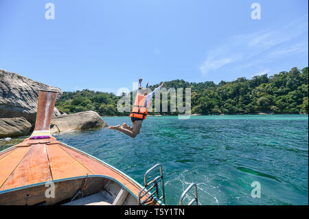 Turista il salto sulla barca di legno nel mare tropicale in estate Foto Stock