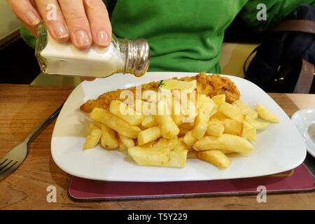 Un tradizionale pesce inglese Chip e pasto servito su un tavolo in un pesce e ristorante di chip. Le piastre contiene martoriato fresca Cod, patatine e tè Foto Stock