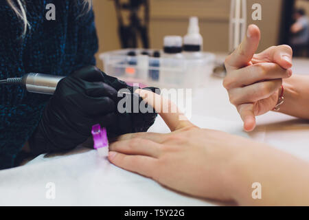 Mani in guanti si preoccupa per mano d'uomo chiodi. Manicure salone di bellezza. Foto Stock