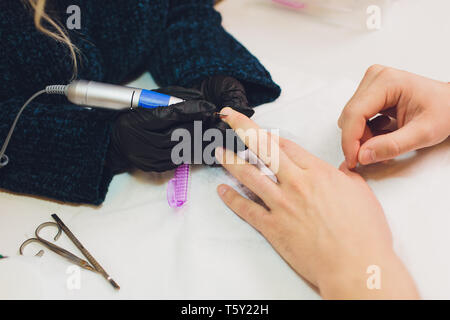 Mani in guanti si preoccupa per mano d'uomo chiodi. Manicure salone di bellezza. Foto Stock