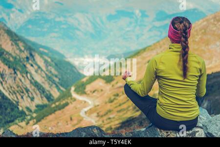 Giovane donna nel suo 30s meditazione Yoga sul Vertice di alpini. Foto Stock