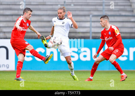 Di Sandhausen, Germania. 27 apr, 2019. Calcio: Seconda Bundesliga, SV Sandhausen - Holstein Kiel, trentunesima Giornata a Hardtwald Stadium. iels Jonas Meffert (l-r), Sandhausens Rurik Gislason e Kiels Laszlo Benes lotta per la palla. Credito: Uwe Anspach/dpa - NOTA IMPORTANTE: In conformità con i requisiti del DFL Deutsche Fußball Liga o la DFB Deutscher Fußball-Bund, è vietato utilizzare o hanno utilizzato fotografie scattate allo stadio e/o la partita in forma di sequenza di immagini e/o video-come sequenze di foto./dpa/Alamy Live News Foto Stock