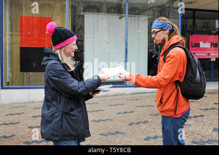 Un protestore anti-UKIP che dà un opuscolo a un acquirente di passaggio nel centro della città in vista delle elezioni locali, Wakefield, West Yorkshire, Inghilterra, Regno Unito, 27th aprile 2019. Foto Stock