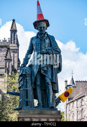 Il Royal Mile di Edimburgo, Scozia, Regno Unito, 27 aprile 2019. Festaioli decorano le Adam Smith statua con traffico coni nel sole di primavera come egli guarda i turisti di passaggio Foto Stock