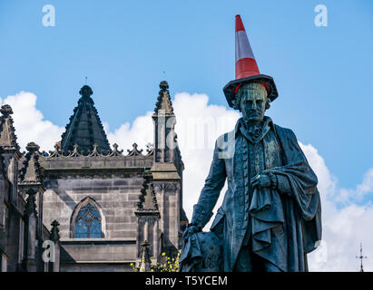 Il Royal Mile di Edimburgo, Scozia, Regno Unito, 27 aprile 2019. Festaioli decorano le Adam Smith statua con cono di traffico nel sole primaverile come egli guarda i turisti di passaggio Foto Stock