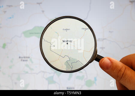 Niamey, Niger. Mappa politico. Visualizzazione della città concetto illustrativa sullo schermo attraverso la lente di ingrandimento in mano. Foto Stock