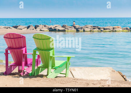 Due luminose terrazze colorate o sedie da spiaggia di Kew balmy spiaggia che si affaccia sul lago Ontario a Toronto Est, Canada Foto Stock