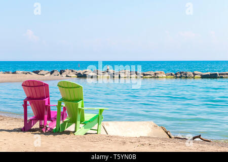 Due luminose terrazze colorate o sedie da spiaggia di Kew balmy spiaggia che si affaccia sul lago Ontario a Toronto Est, Canada Foto Stock