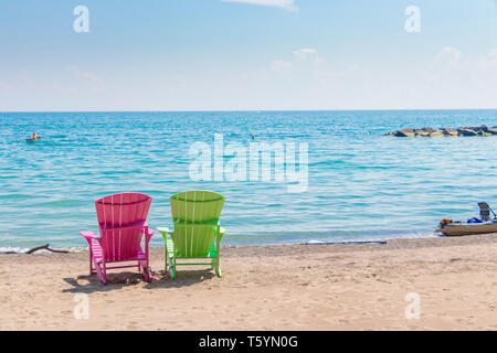 Due luminose terrazze colorate o sedie da spiaggia di Kew balmy spiaggia che si affaccia sul lago Ontario a Toronto Est, Canada Foto Stock