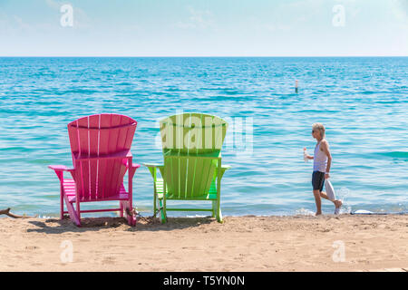 Due luminose terrazze colorate o sedie da spiaggia di Kew balmy spiaggia che si affaccia sul lago Ontario a Toronto Est, Canada Foto Stock