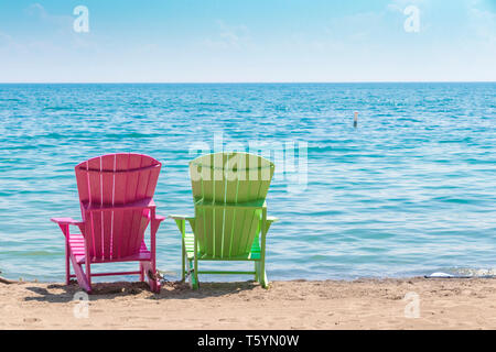 Due luminose terrazze colorate o sedie da spiaggia di Kew balmy spiaggia che si affaccia sul lago Ontario a Toronto Est, Canada Foto Stock