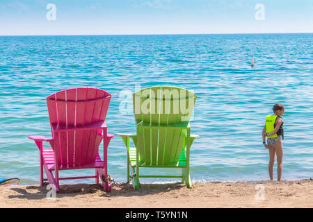 Due luminose terrazze colorate o sedie da spiaggia di Kew balmy spiaggia che si affaccia sul lago Ontario a Toronto Est, Canada Foto Stock