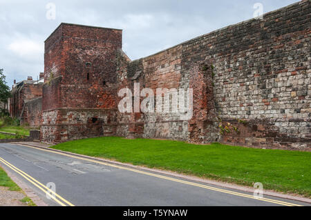 Grigio di un cielo nuvoloso di telai oltre la medievale a due piani piastrella quadrata torre costruita a filo contro il rosso dei blocchi di pietra arenaria della città di Carlisle arginato pareti Foto Stock