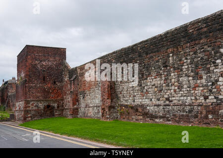 Grigio di un cielo nuvoloso di telai oltre la medievale a due piani piastrella quadrata torre costruita a filo contro il rosso dei blocchi di pietra arenaria della città di Carlisle arginato pareti Foto Stock