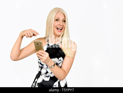 Felice donna attraente a ridere come lei punti in un messaggio sul suo telefono cellulare Foto Stock