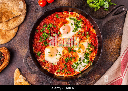 Shakshuka in una padella. Le uova in camicia in pomodoro piccante salsa di pepe. Foto Stock