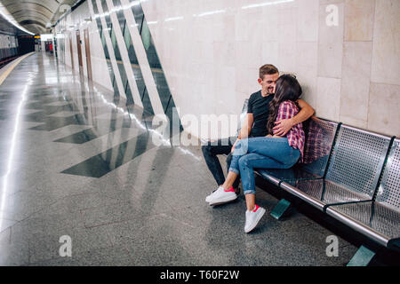 Giovane uomo e donna utilizzare la metropolitana. Matura in metropolitana. Bella giovane uomo e donna sedersi insieme. Egli abbracciare il suo bacio e. Amore a prima vista. Urbano VI Foto Stock