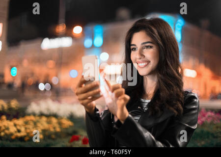 Donna controllo reti sociali, passeggiate nella città di notte Foto Stock