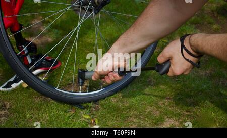 Giovane uomo con le mani in mano il pompaggio di aria nel pneumatico di una bicicletta utilizzando una pompa a mano - immagine Foto Stock