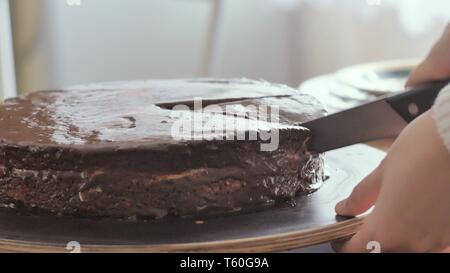 Ragazza taglia un pezzo di torta al cioccolato e lo mette su una piastra di close-up shot Foto Stock