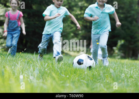 Dei bambini felici giocando a calcio in estate park Foto Stock